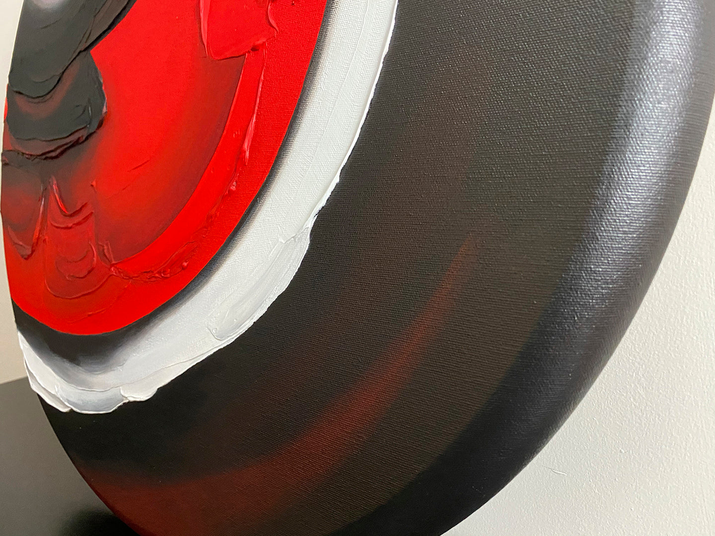 Abstract, acrylic and mixed-media painting close-up of the texture paste, red, black, grey, and white acrylic paint on round canvas focusing on the beautiful curved-edges 3