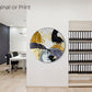 Abstract, acrylic painting on a round canvas with curved-edges shown on a white office reception wall next to a media shelf and dark feature wall.
