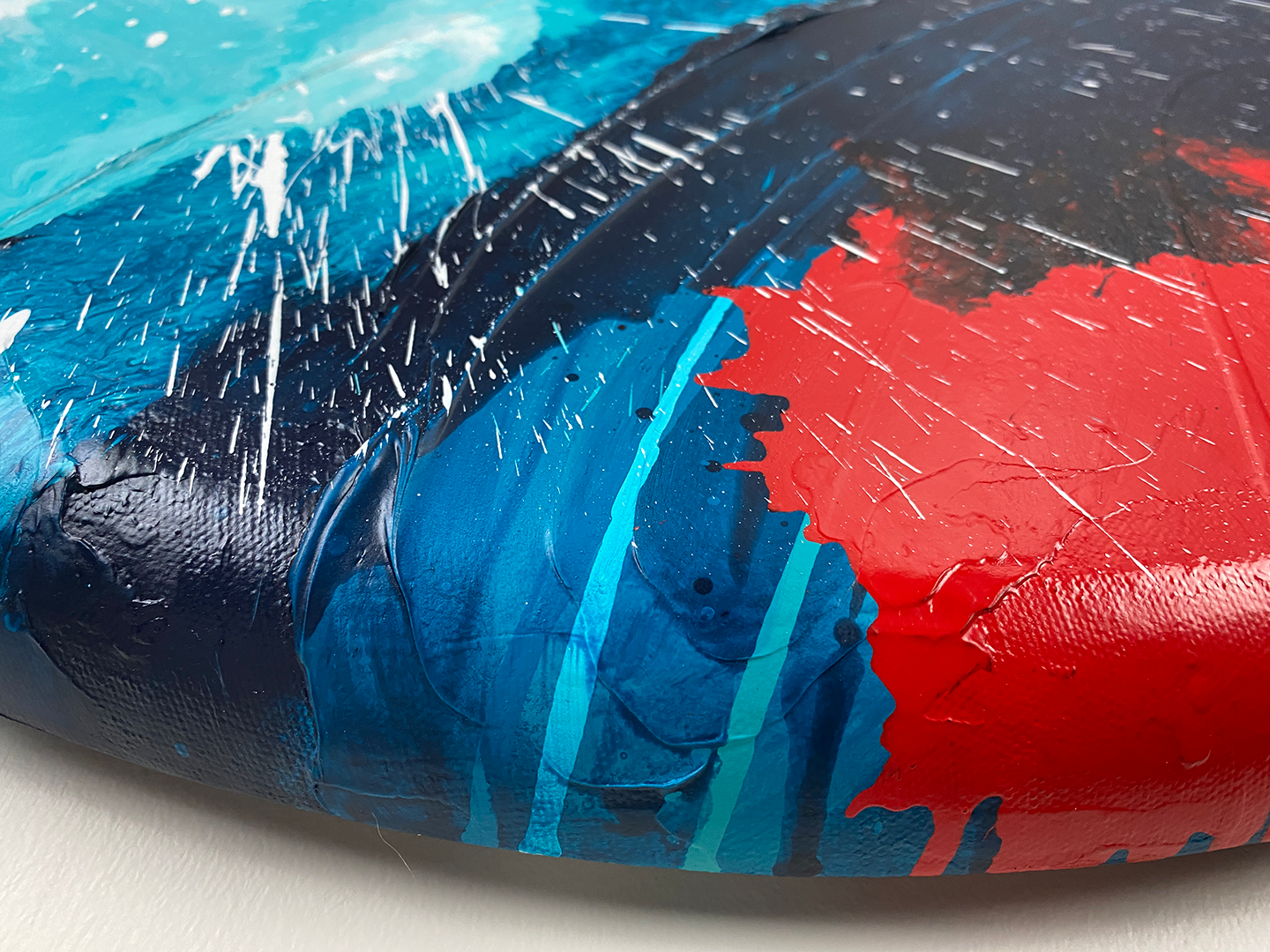 Abstract, expressionism, acrylic painting close-up showing the curved edge 2 and tex-ture. Overlapping explosions of dark blue, turquoise, bright red and white