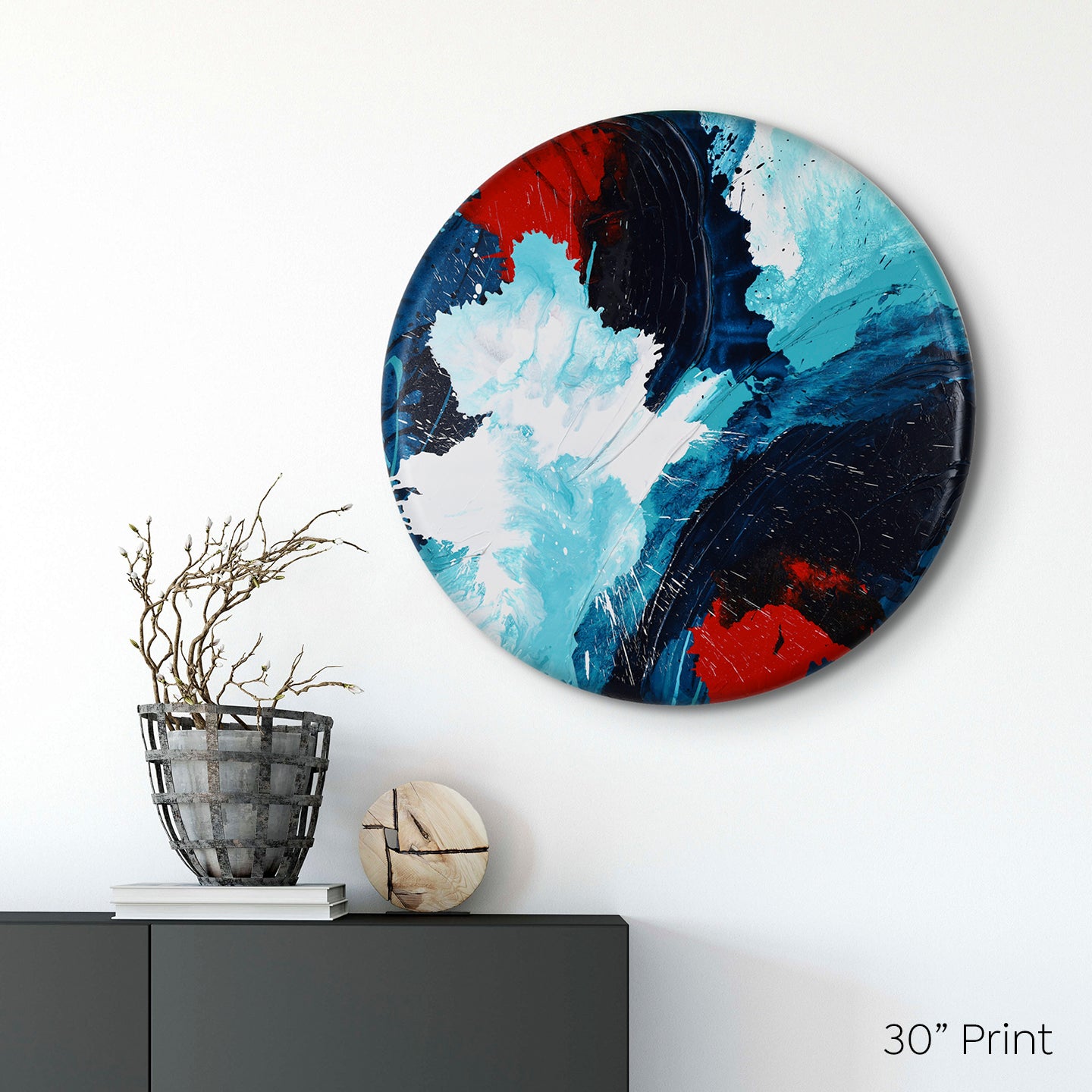 Abstract, expressionism, acrylic 30” print: overlapping explosions of dark blue, turquoise, bright red and white on a medium white wall above a dark sideboard